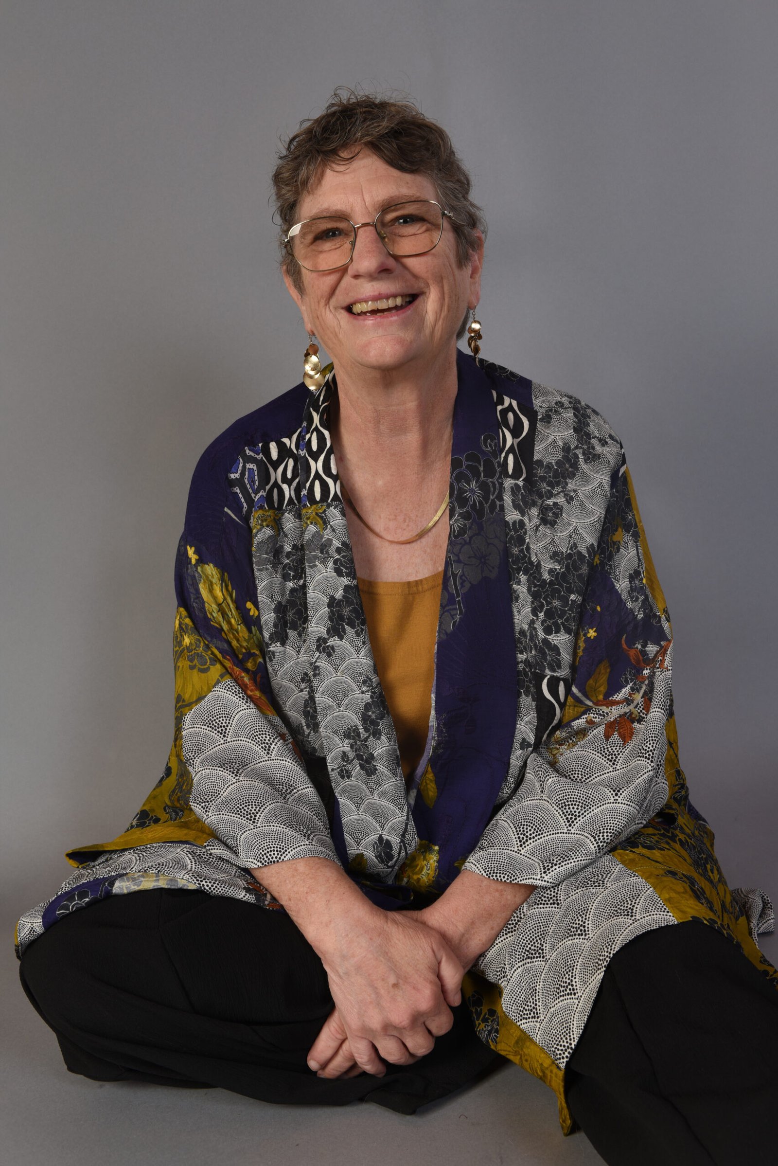A woman therapist sitting on the ground with a leg out.