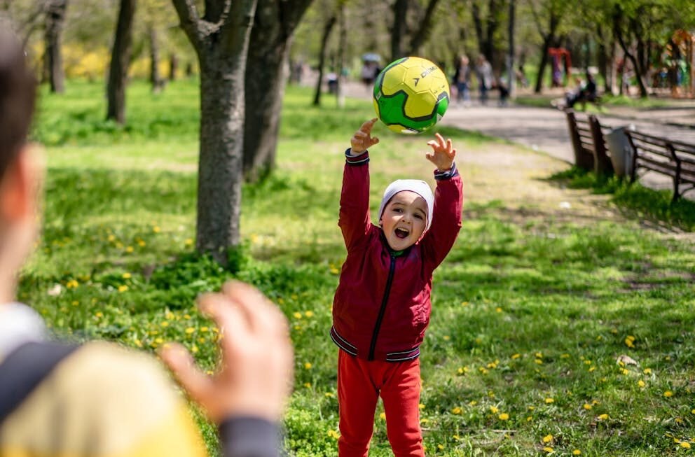 two boys playing catch with a green ball Photo by Alex P from Pexels: https://www.pexels.com/photo/a-boy-catching-a-ball-12955786/